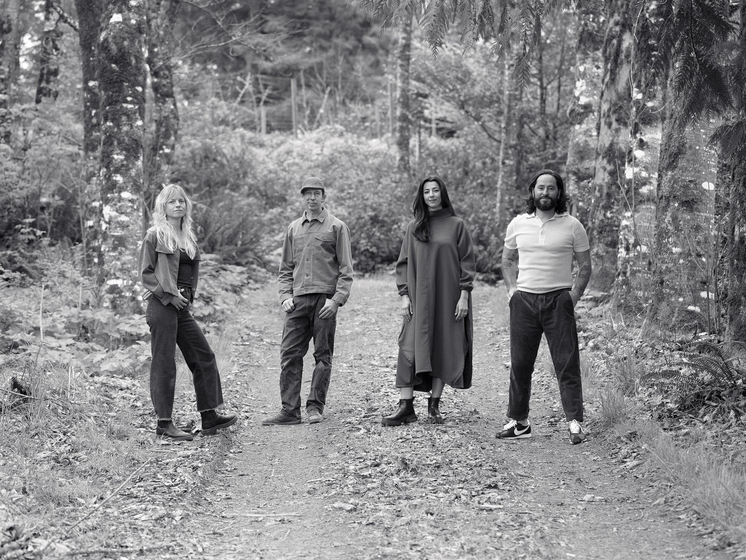 The Perpetually Devastated team — Lauren Criner, Jeffrey Ostercamp, Negar Vali, and Parker Bolden — standing on a forest path near the Coquille studio.